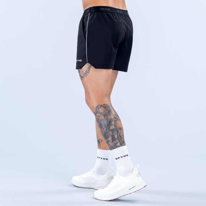Men's black 4-inch training shorts, side view, elastic waistband and white piping