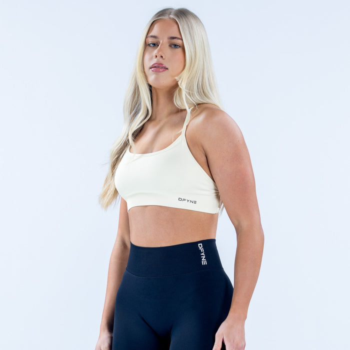 White sports bra with scoop neckline, thin straps, and open back