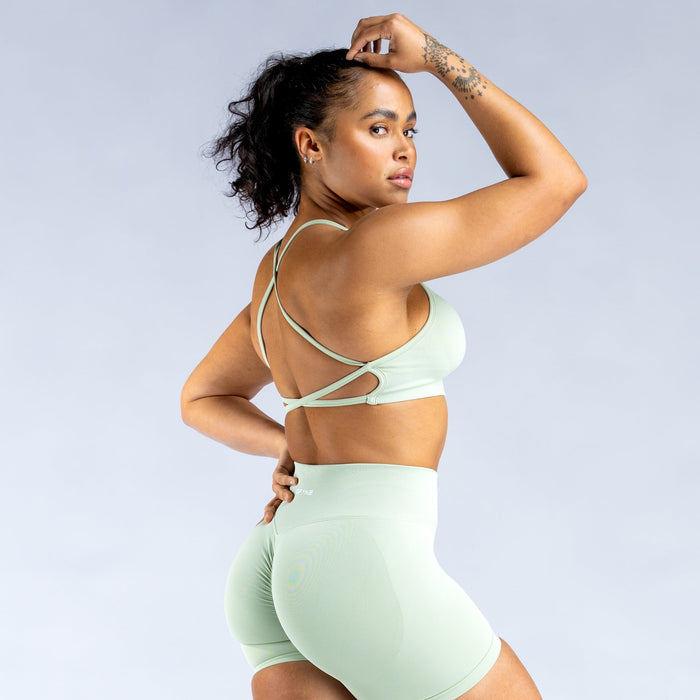 Mint green open-back sports bra with thin crisscross straps and scooped front