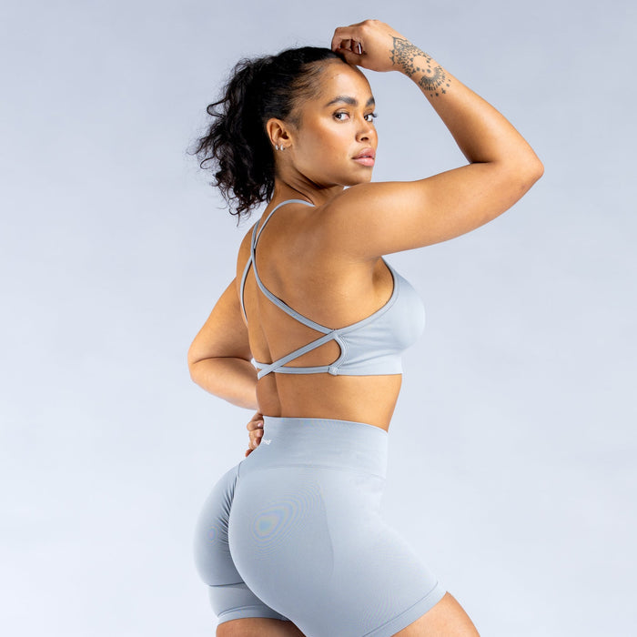 Light blue backless sports bra showing crisscross back straps and wide band