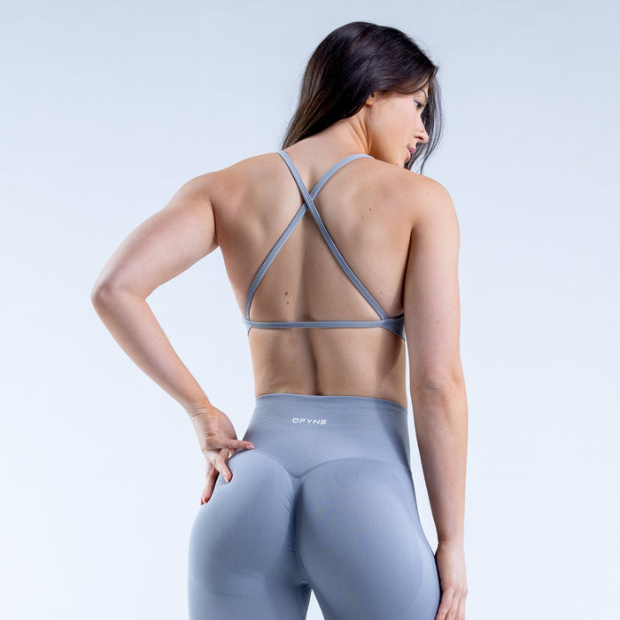Back view of high-neck sports bra in light blue-gray with crossed straps