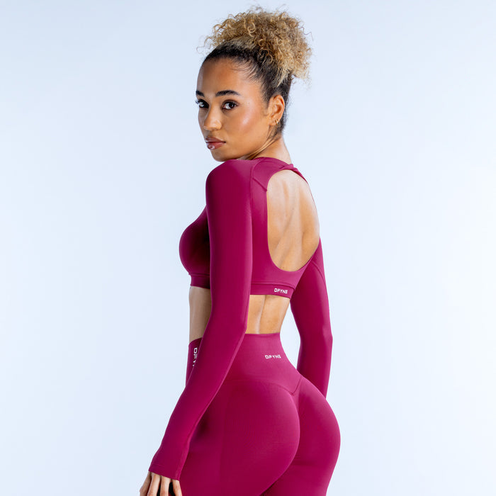 Magenta long-sleeve crop top with open back cutout and fitted scoop neckline
