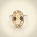 Ring with a large faceted yellow gemstone on a white background