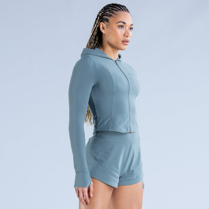 Teal-blue cropped zip hoodie with front zipper and hood detail, side profile
