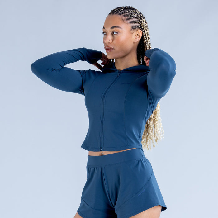 Blue zip-front hoodie and shorts set, hands adjusting hood neckline