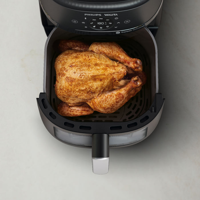 Philips Air Fryer with a roasted chicken inside on a light gray background