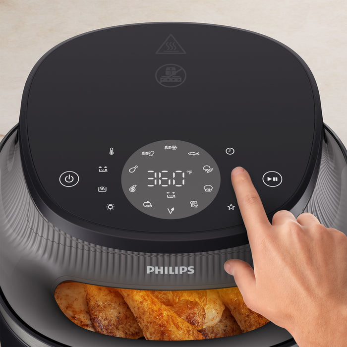 Hand pressing a button on a Philips air fryer with digital display
