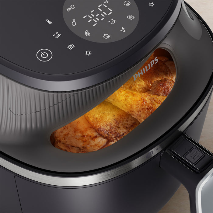 Philips air fryer with food inside, showing digital display and control panel.
