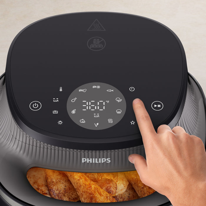Hand pressing a button on a Philips air fryer with digital display