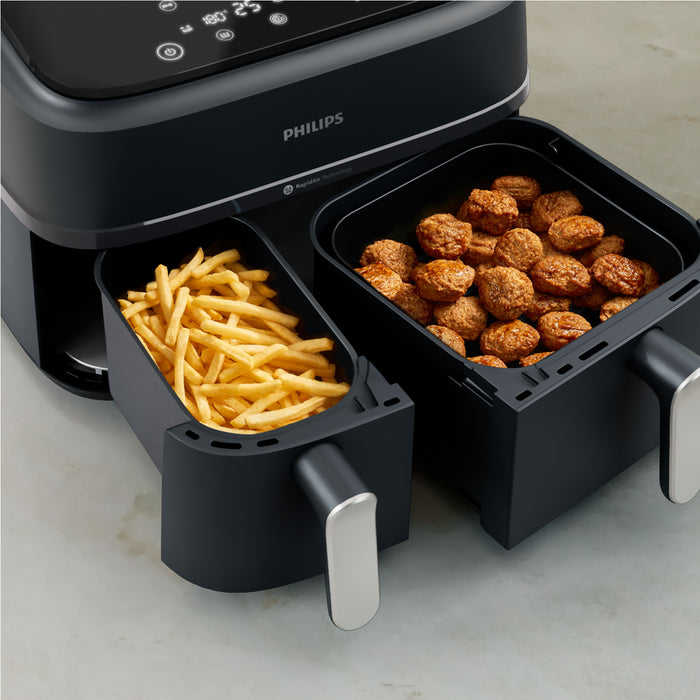 Philips air fryer with two compartments, one containing fries and the other containing meatballs.