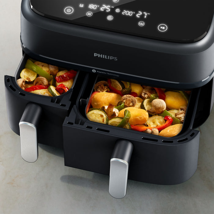 Philips dual basket air fryer with food inside on a light gray background