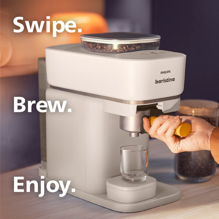 Philips barista coffee machine with a hand holding a glass, set against a blurred background.