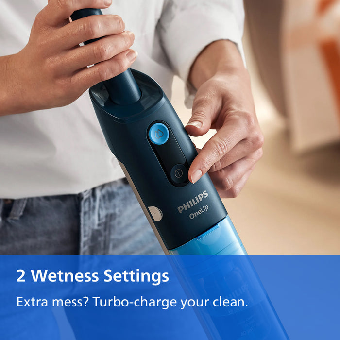 A person holding a Philips OneClean cordless vacuum cleaner, showing the top and side of the device with a blue button. The image includes a blue text banner at the bottom that reads '2 Wetness Settings Extra mess? Turbo-charge your clean.