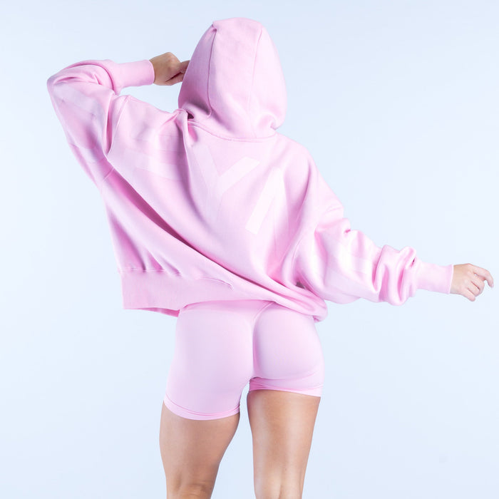 Light pink hoodie with hood up, long sleeves, and kangaroo pocket; matching biker shorts