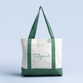 Canvas tote bag with green handles and bottom, white front panel with logo print